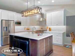 Elegant kitchen remodel with white cabinets, stainless steel appliances, large island, and modern lighting by Premier Kitchen & Bath.