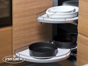 Corner cabinet with an appliance garage featuring pull-out shelves holding black and white baking dishes